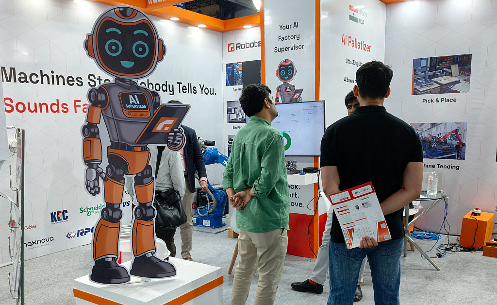 Two men look at a cutout of a robot on an exhibit floor